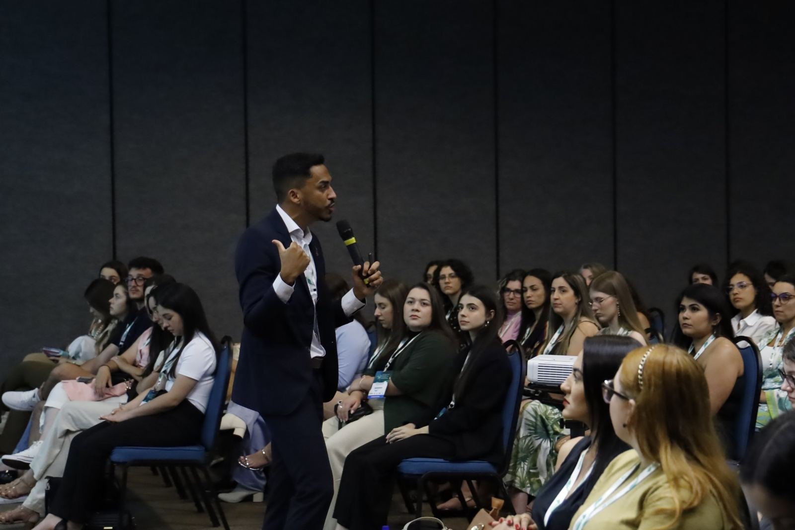 Thiago Nascimento palestrando com microfone para uma plateia em um congresso